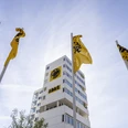 ADAC Nordrhein e.V. Yellow ADAC flags fly in front of a modern high-rise building under a clear sky.