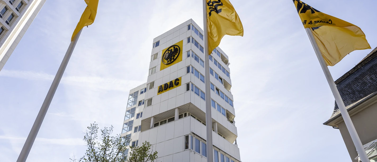 ADAC Nordrhein e.V. Yellow ADAC flags fly in front of a modern high-rise building under a clear sky.