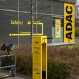 ADAC Radservice Station Gelbe ADAC-Radservicestation vor Gebäude mit Wegweiser und abgestelltem E-Scooter.