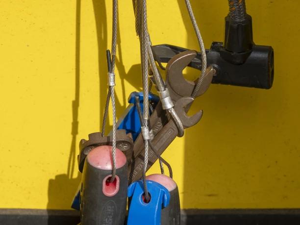 ADAC Radservice Station An Kabeln gesicherte Fahrradwerkzeuge vor einer gelben Fläche