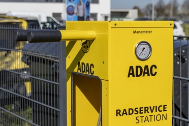 ADAC bike service station Yellow ADAC bike service station with pressure gauge and tools in front of a fence.