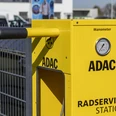 ADAC Radservice Station Gelbe ADAC-Radservicestation mit Manometer und Werkzeug vor einem Zaun.