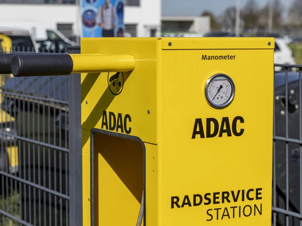 ADAC Radservice Station Gelbe ADAC-Radservicestation mit Manometer und Werkzeug vor einem Zaun.