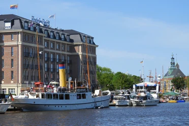 Emden Matjestage.jpg Weißes Traditionsschiff im Emder Hafen vor dem Hotel am Delft zu den Matjestagen.
