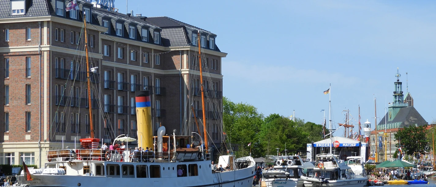 Emden Matjestage.jpg Weißes Traditionsschiff im Emder Hafen vor dem Hotel am Delft zu den Matjestagen.
