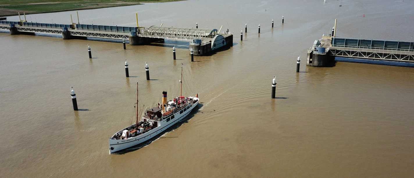 Fahrt durch Emssperrwerk.jpg Historisches Schiff Prinz Heinrich passiert das geöffnete Emssperrwerk auf der Ems.