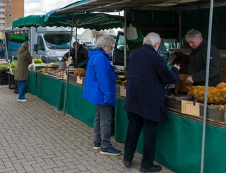 Kunden stehen an Wochenmarktständen