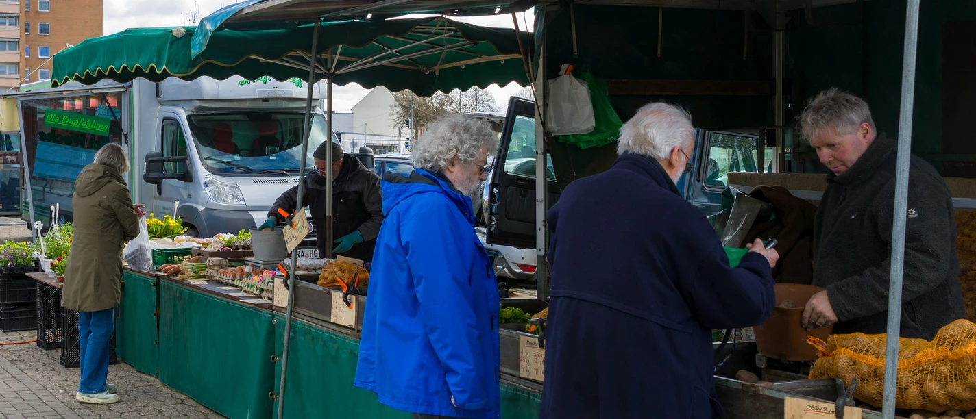 Kunden stehen an Wochenmarktständen