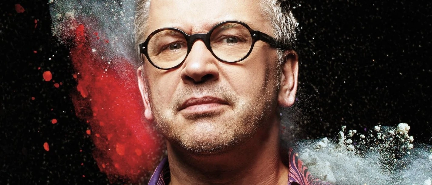 Kabarett-Tage Pilsum 2026: Comedy mit Robert Griess Porträt von Robert Griess mit Brille und buntem Hemd. Im Hintergrund explodiert farbiges Pulver.