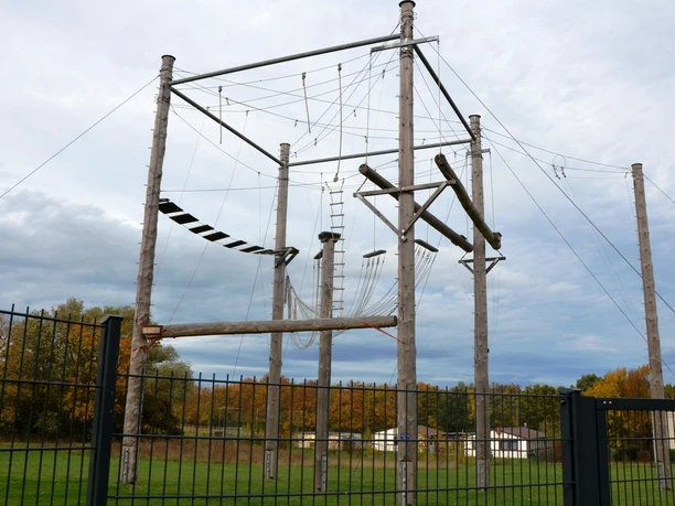 Hochseilgarten_Salzgitter_HD_16zu9.JPG Hohe Holzmasten und Seile des Hochseilgartens Salzgitter vor einem bewölkten Himmel.
