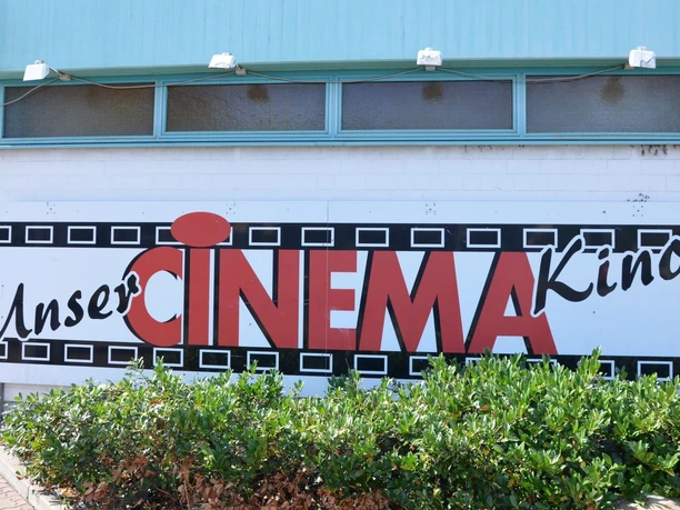 Außenfassade des CINEMA Kinos in Salzgitter mit großem Logo und Schriftzug über grünem Gebüsch.