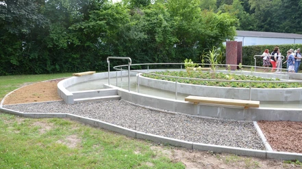 Kneippbecken_Gebhardshagen_HD_16zu9.JPG Rundes Kneippbecken aus Beton mit Edelstahlgeländer und angrenzendem Barfußpfad im Grünen.