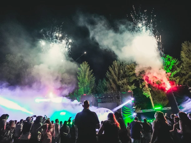PF4.jpg Festivalpublikum feiert nachts vor einer beleuchteten Open-Air-Bühne mit Nebel und Lichteffekten.
