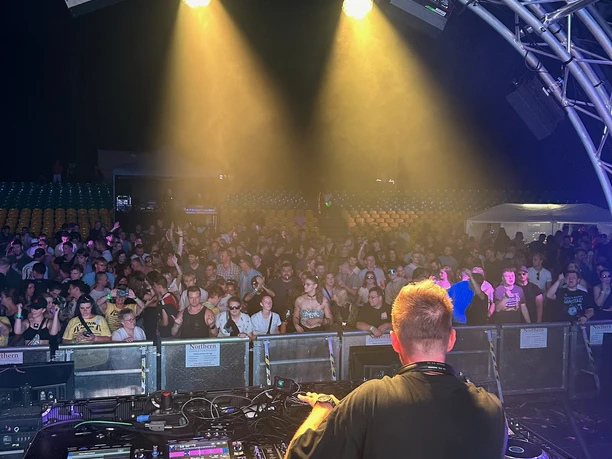 PF3.jpg Ein DJ am Mischpult blickt nachts auf die feiernde Menge beim Planet Future Festival.