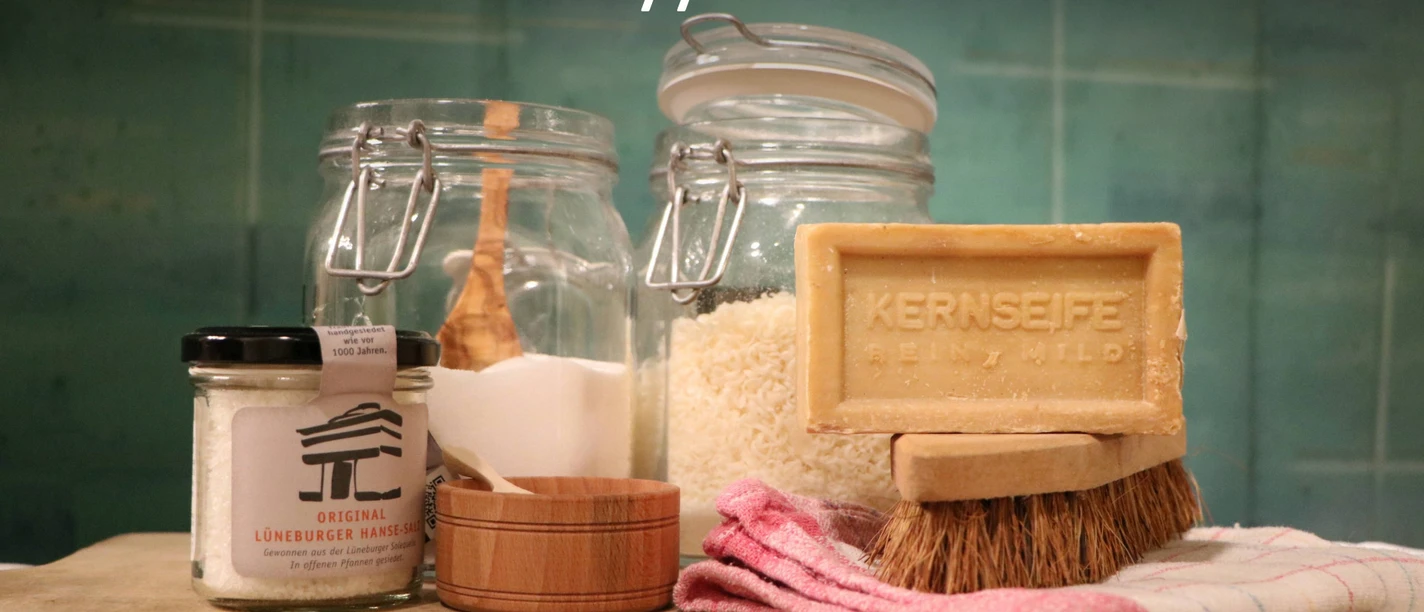 Aktionstag "Blitzblank & brillant günstig" im Salzmuseum Verschiedene selbsthergestellte Waschmittel, Kernseife, Salz und Putzutensilien stehen auf einem Tisch.