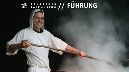Regelmäßige Führung durch das Deutsche Salzmuseum Ein Salzsieder mit weißer Kutte bei der Arbeit an einer dampfenden Siedepfanne.