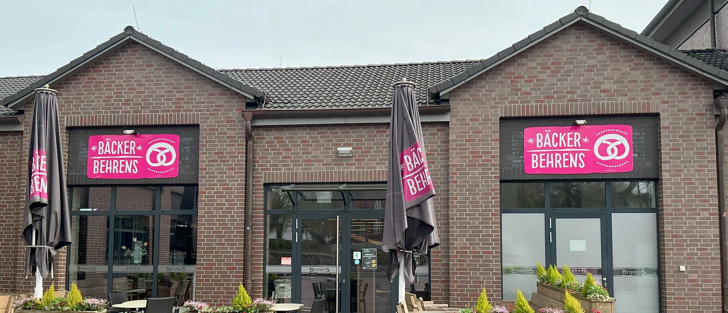 Außenansicht der Bäckerei Behrens: Rotes Backsteingebäude mit bestuhlter Außenterrasse.