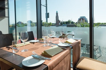 Gedeckter Tisch am großen Fenster mit Blick auf den Loschen-Turm am Bremerhavener Hafen.