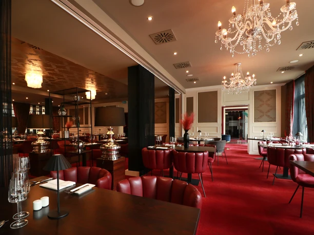 IMG_0313_Restaurant_Weinrot_klein (c) Emina Seiffert_Haverkamp.jpg Eleganter Speisesaal mit roten Sesseln, rotem Teppich, edlen Tischen und Kronleuchtern.