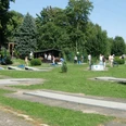 Minigolfplatz_Gebhardshagen_HD_16zu9.jpg Gäste spielen bei sonnigem Wetter auf einer grünen Minigolfanlage mit grauen Bahnen.