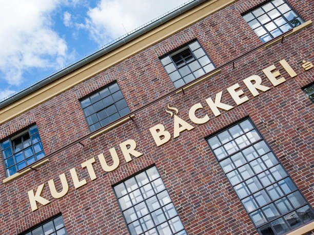 Kulturbäckerei Backsteinfassade mit großen Sprossenfenstern und dem großen Schriftzug Kultur Bäckerei.