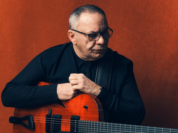 Bireli-Lagrene-(c) A. Berthet.jpg Jazz-Musiker Bireli Lagrene mit Gitarre vor roter Wand