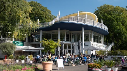 Park Café im Rheinpark Außenbereich eines modernen Cafés mit vielen Gästen vor einem hellen Rundbau im Grünen
