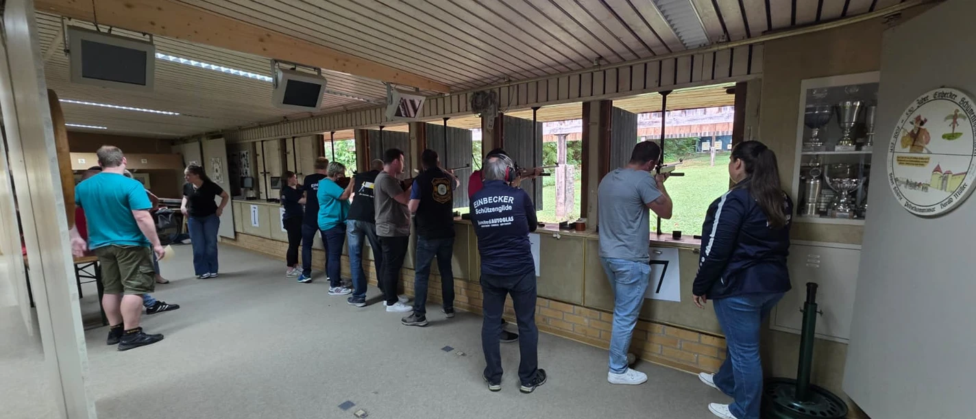 Einbecker Schützengilde.jpeg Teilnehmer stehen am Schießstand in einer Reihe und zielen mit Gewehren auf die Zielscheiben.