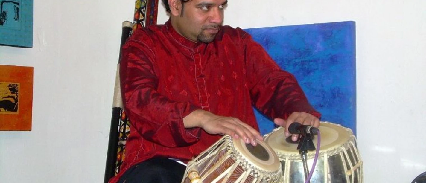 Ein Mann spielt sitzend auf einem indischen Instrument.