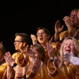Gospelchor Begeisterte Chorsänger in goldenen Gewändern klatschen und singen voller Freude beim Gospelkonzert.