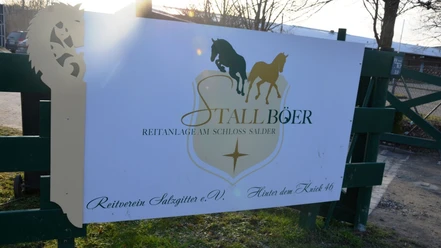 Schild der Reitanlage Stall Böer und des Reitvereins Salzgitter an einem grünen Zaun.
