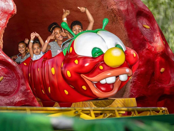 raupenbahn.jpg Lachende Kinder in einer roten Raupenbahn, die aus einer riesigen Erdbeere fährt.