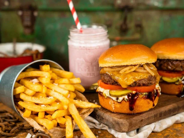 burger.jpg Zwei saftige Burger, goldgelbe Pommes frites und ein rosa Milchshake.