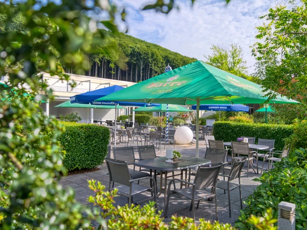 Biergarten der Wiehen-Therme mit Tischen unter grünen Sonnenschirmen im Gartenbereich