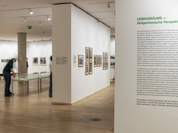 The Photographic Collection/SK Stiftung Kultur Exhibition space with photographs on white walls and visitors in motion