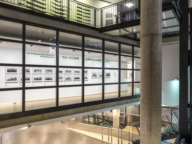 Die Photographische Sammlung/SK Stiftung Kultur Fotogalerie hinter Glas mit geradlinigem Innenraum und gerahmten Schwarzweißaufnahmen.