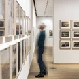 The Photographic Collection/SK Stiftung Kultur Exhibition room with many framed photographs and a blurred person looking at them