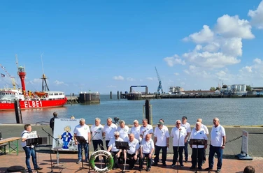 Bild am Hafen Ein Shanty-Chor singt am sonnigen Hafen vor dem roten Traditionsschiff ELBE 1.