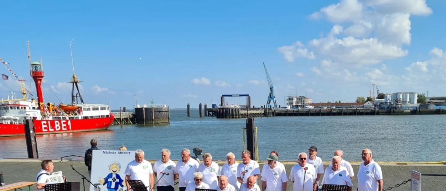 Bild am Hafen Ein Shanty-Chor singt am sonnigen Hafen vor dem roten Traditionsschiff ELBE 1.