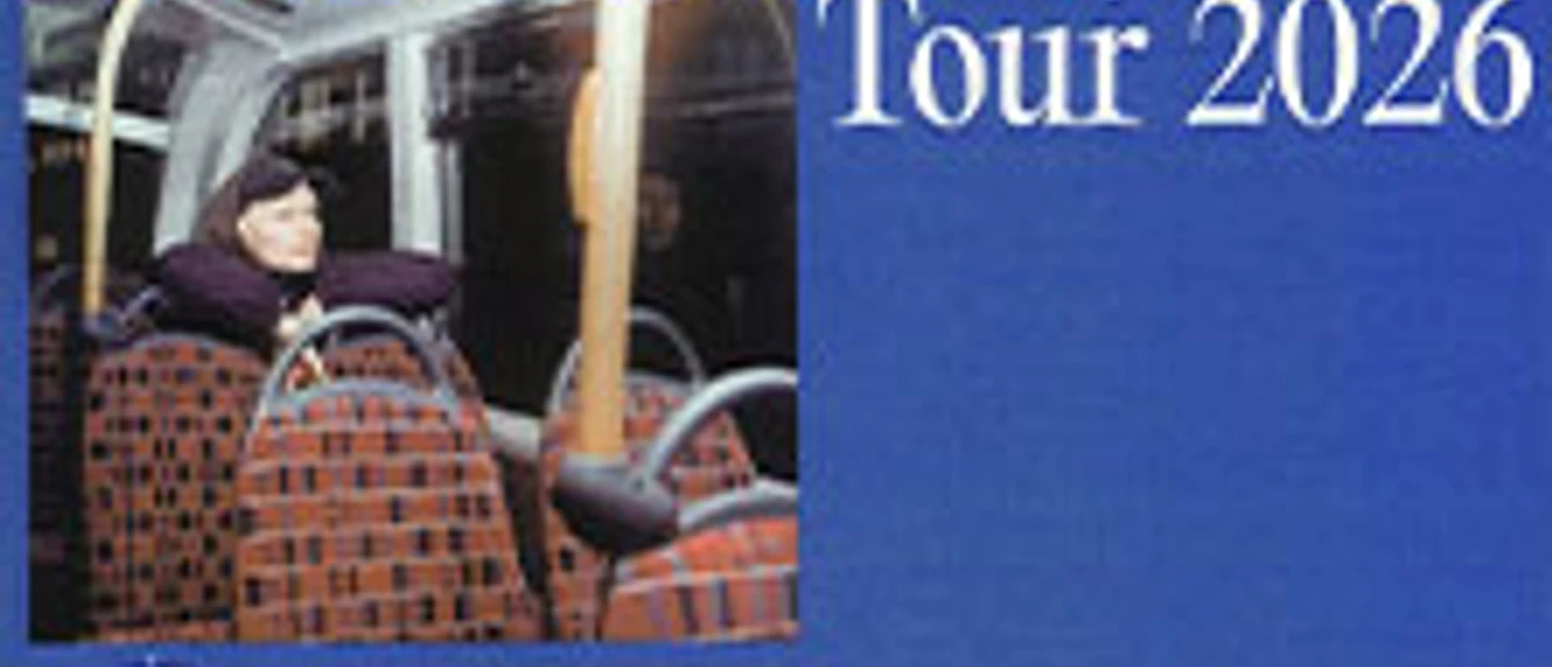 Plakat mit Tourtitel und einer Person, die allein in einem Bus auf gepolsterten Sitzen sitzt