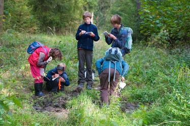 Kinder mit Zetteln und Stiften in der Natur