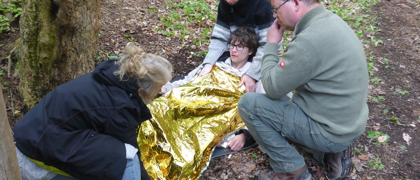 Menschen arbeiten mit einer Rettungsdecke im Wald