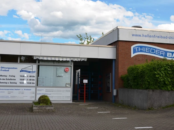 Hallenfreibad_Thiede_HD_16zu9.JPG Eingangsbereich des Thieder Bads in Salzgitter mit Öffnungszeiten und Preisen an der weißen Fassade.