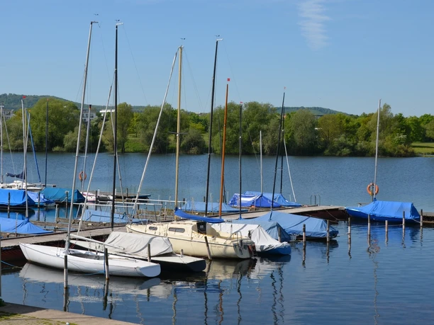 Segelhafen_Salzgittersee_HD_16zu9.JPG Segelboote am Holzsteg auf dem Salzgittersee vor grünem Ufer unter blauem Himmel.