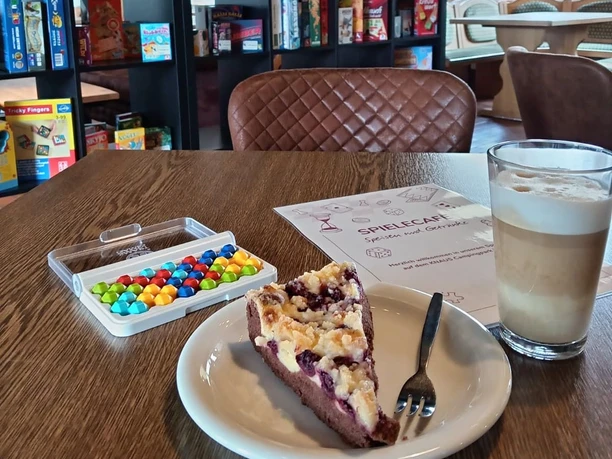 Spielcafe Knaus Campingpark Wingst Kuchen, Kaffee und Spiele auf dem Holztisch im Spielcafé Wingst laden zu einer Auszeit ein.
