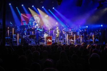Bandfoto Konzert der Big Band der Bundeswehr auf einer blau beleuchteten Bühne vor großem Publikum.