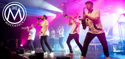Muckasäck EMC Die Band Muckasäck spielt live auf einer pink beleuchteten Bühne mit Blasinstrumenten und Gesang.