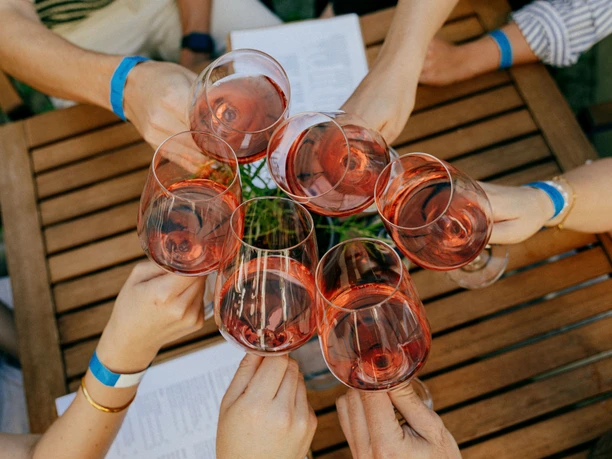 Mehrere Weingläser werden zum Anstoßen in die Mitte gehalten.