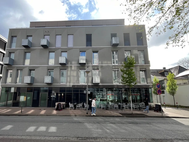 Limehome Modernes Apartmenthaus mit grauer Fassade und kleinen Balkonen in zentraler Lage