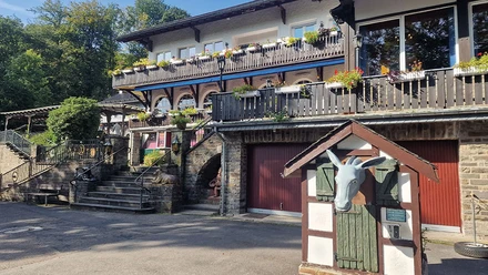 Märchenwald Fachwerkgebäude mit Blumenschmuck, Steintreppen und einer markanten Eselfigur im Vordergrund.